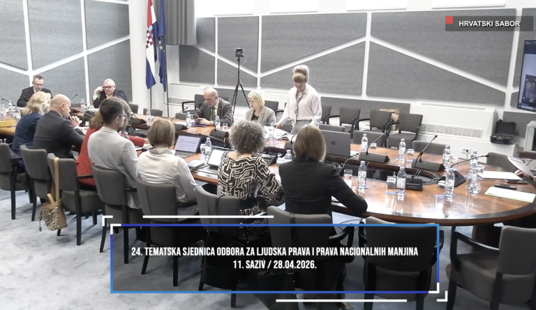 Sudionici tematske sjednice Odbora za ljudska prava i prava nacionalnih manjina u Hrvatskom saboru sjede za velikim stolom, raspravljaju i koriste prijenosna računala; u prostoru su vidljive zastave Hrvatske i Europske unije te natpis o sjednici.